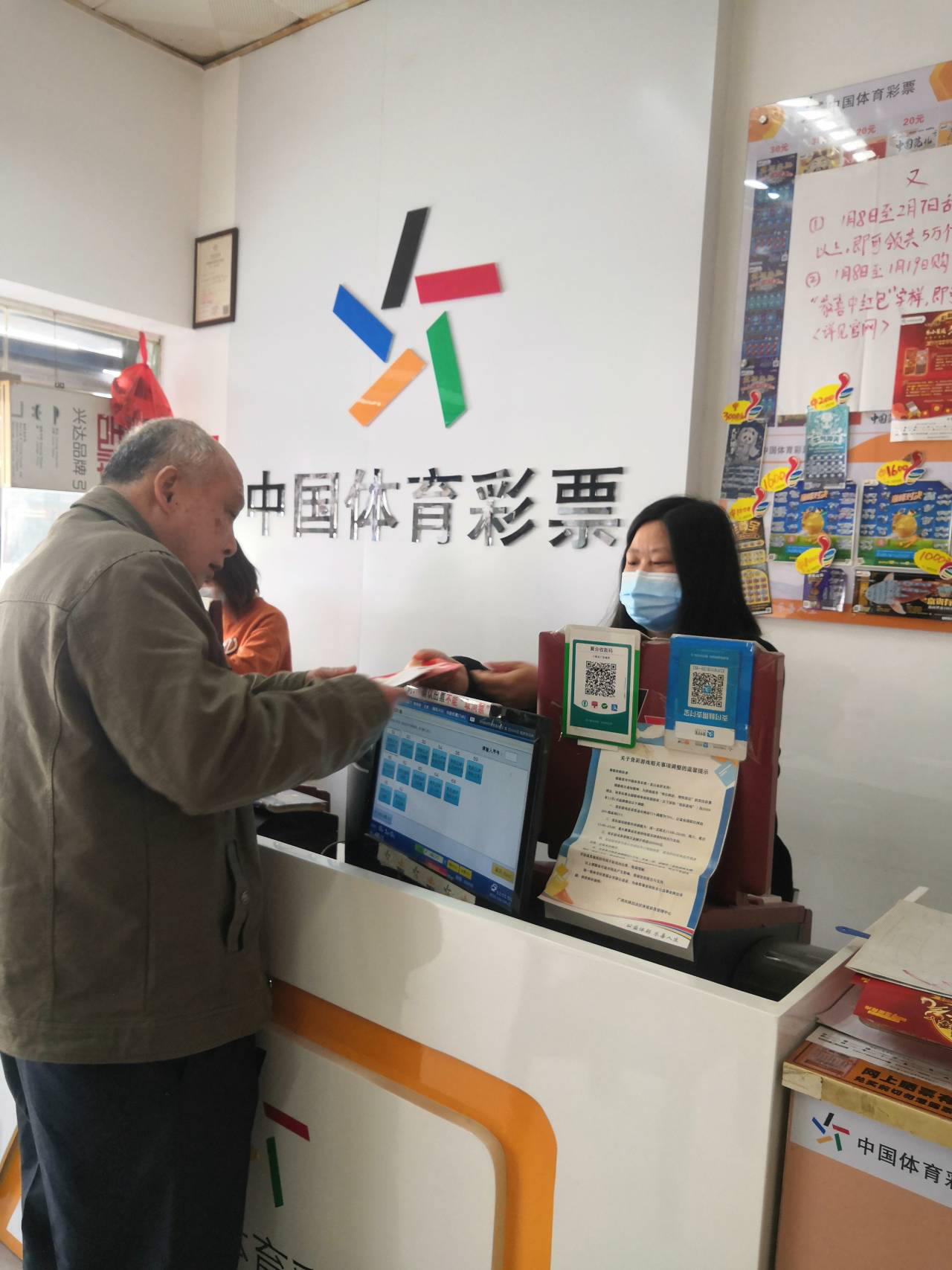 梧州一体彩店销售员在为购彩者提供兑奖和投注服务